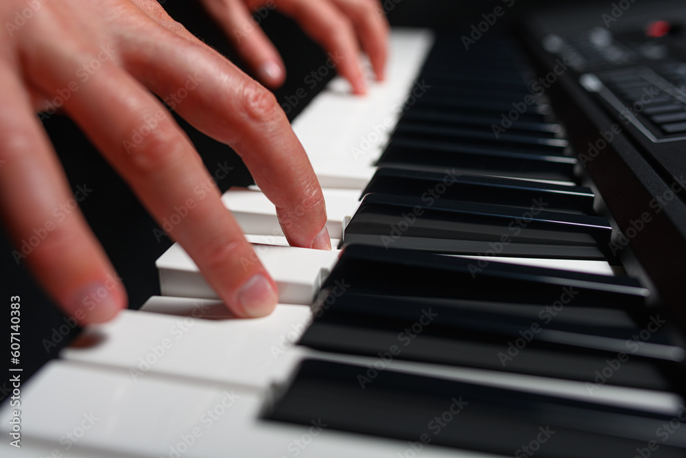 Playing a synthesizer on a dark background. The musician plays the synthesizer.