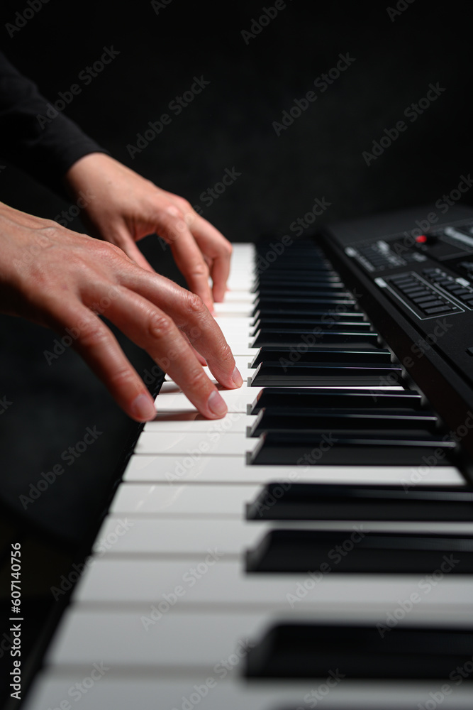 Playing a synthesizer on a dark background. The musician plays the synthesizer.