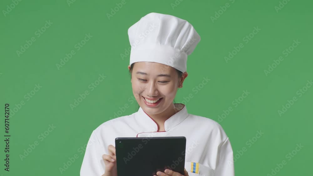 Close Up Of Asian Woman Chef Smiling And Pointing To Tablet In Her Hand While Standing In The Green Screen Background Studio
Close Up Of Asian Woman Chef Smiling And Pointing To Tablet In Her Hand While Standing In The Green Screen Background Studio