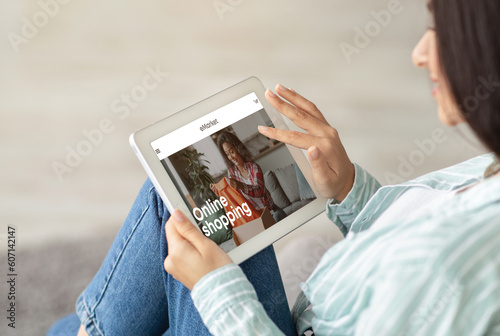 Millennial indian lady using tablet with fashion blog on screen at home
