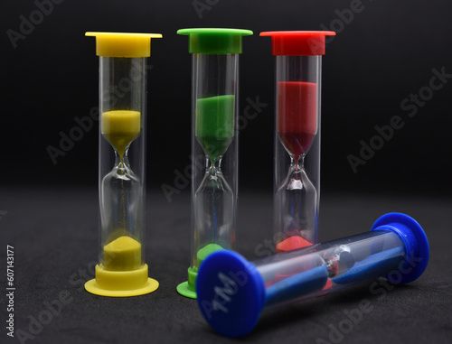 Multicolored glass hourglass on a black background. Vintage hourglass.