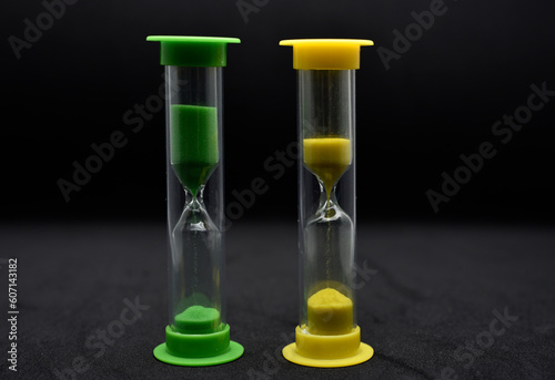 Multicolored glass hourglass on a black background. Vintage hourglass.