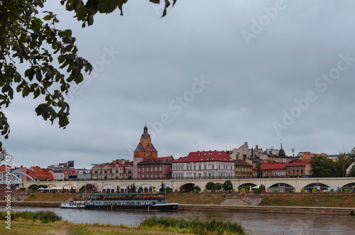 European City Landscape: Towers, River, and Parked Ship