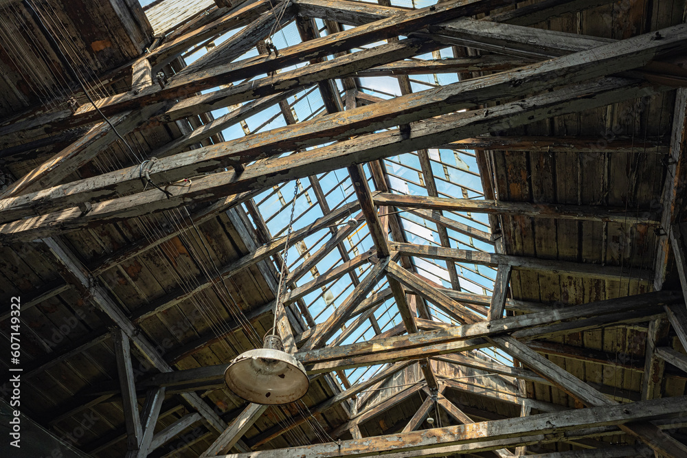 Bottom view of an old wooden roof with windows in an abandoned workshop on a sunny day.