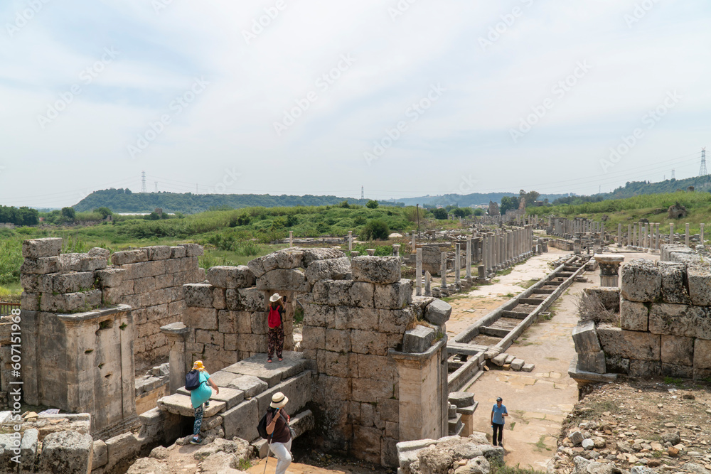 Ruins of Perge (Perga) in the province of Antalya, Türkiye. View of the ancient Greek city. Tourists walk in a popular tourist destination in Turkey