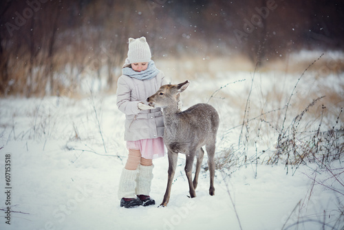 Girl with reindeer in the park in winter 