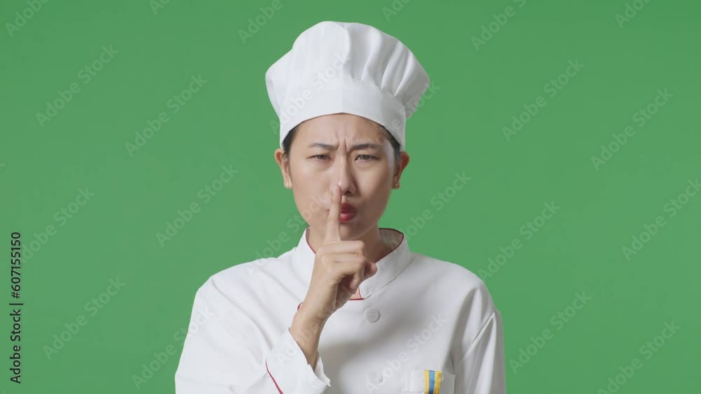 Close Up Of Asian Woman Chef Looking At Camera And Making Shh Gesture In The Green Screen Background Studio
