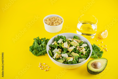 Kale avocado pine nuts cheese salad with lemon dressing in a bowl