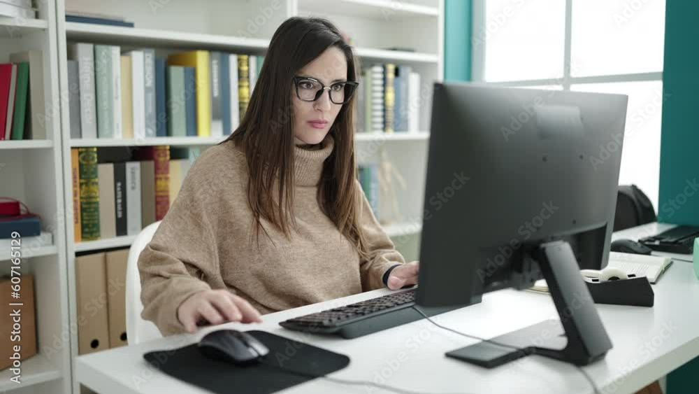 Beautiful hispanic woman student using computer studying at library university