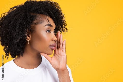Serious pretty young african american curly woman whispering good news