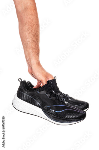 Pair of new unbranded black sport running shoes or sneakers in male hand isolated on white background with clipping path