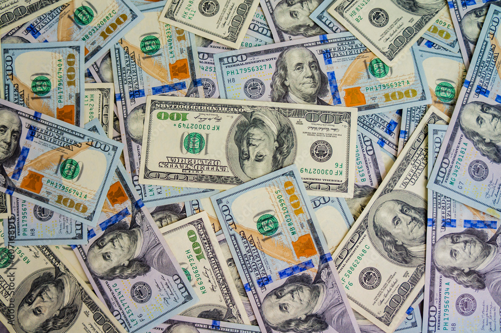 Pile of dollars lies on the table. One hundred dollar bills dumps on table. Background for design from lot of money. Close-up. Texture of American dollars. View from above Pile of dollars lies on the table. One hundred dollar bills dumps on table. Background for design from lot of money. Close-up. Texture of American dollars. View from above