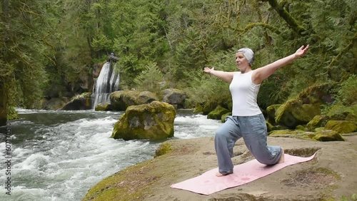50 Year Old Woman Practicing Yoga on a rocky beach in front of a l waterfall photo