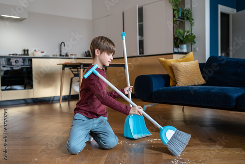 Little boy sweeping floor in living room, kid doing daily regular household chores and helping parents around house, gain important life skills. Children and housework concept