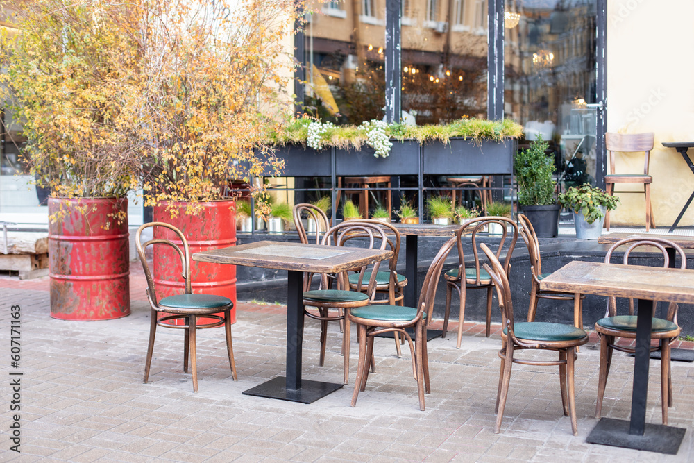 Empty cafe with terrace with tables and wooden chairs. Street vintage exterior of restaurant. Furniture for coffee shop in street in Europe. Typical view of Parisian street with tables of cafe	