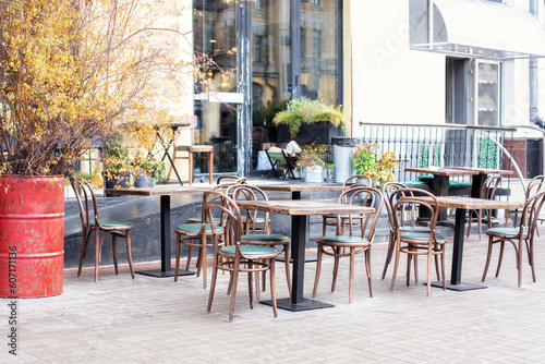 Empty cafe with terrace with tables and wooden chairs. Street vintage exterior of restaurant. Furniture for coffee shop in street in Europe. Typical view of Parisian street with tables of cafe 