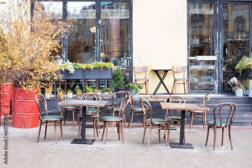 Empty cafe with terrace with tables and wooden chairs. Street vintage exterior of restaurant. Furniture for coffee shop in street in Europe. Typical view of Parisian street with tables of cafe  © stock_studio
