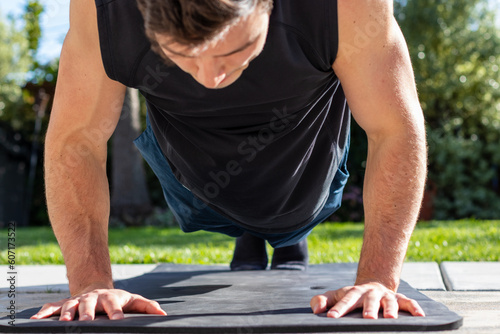Young adult male doing a push-up during an afternoon at-home workout on a yoga mat during the coronavirus pandemic.