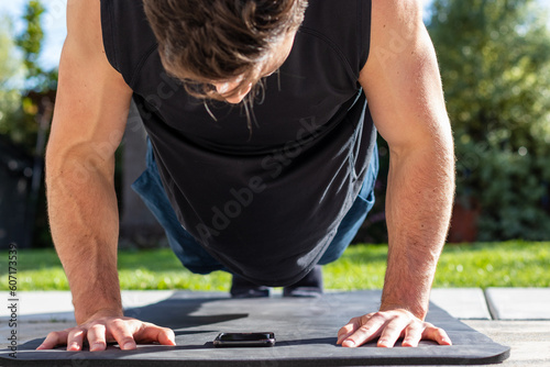 Young adult male doing a push-up during an afternoon at-home workout on a yoga mat during the coronavirus pandemic.