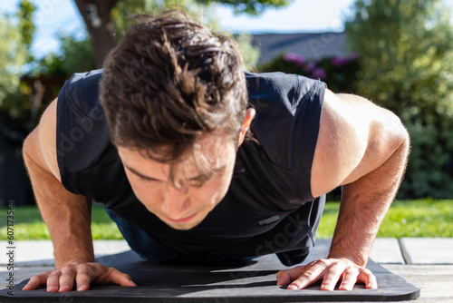 Young adult male doing a push-up during an afternoon at-home workout on a yoga mat during the coronavirus pandemic.