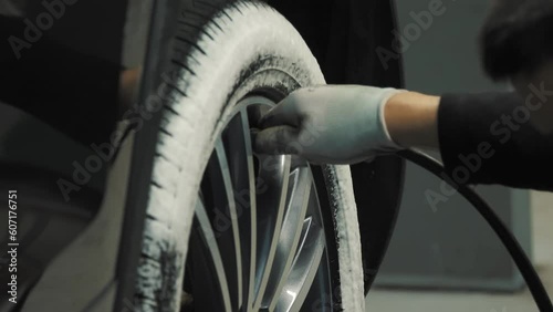 Tire. Car service. In the auto service, an employee, using specialized equipment, inflates the wheel with air and measures the tire pressure after installing a new tire on the car rim. A technical photo
