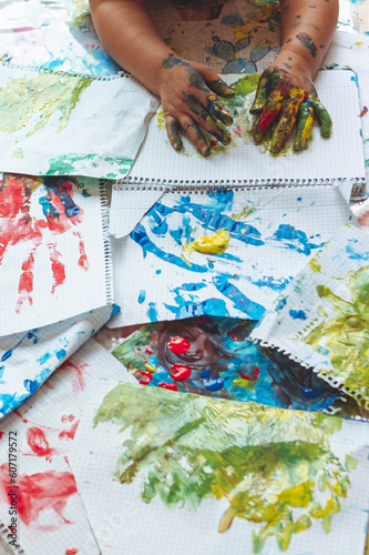 Image of a little boy's hands painting the shape of his hand on sheets of paper