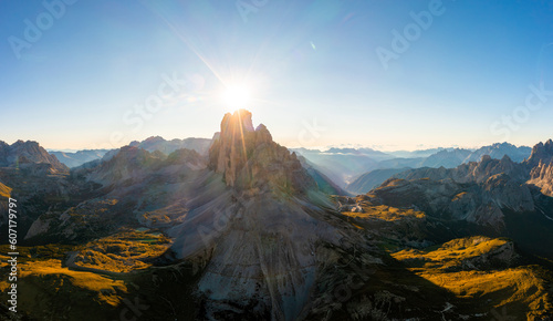Mountain landscape of Tre Cime di Lavaredo at sunrise. Rocky ranges and wide highland valleys in Alps under clear sky aerial view in back lit