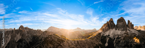 Sun sets on horizon above rocky mountain range. Sand-covered slopes of foothills of Tre Cime di Lavaredo silhouette at sunset aerial view in back lit © vladim_ka