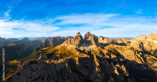 Mountain ranges of Alps under blue sky with white clouds. Rocky peaks above wide shaded canyon. Three peaks of Lavaredo at sunset aerial view