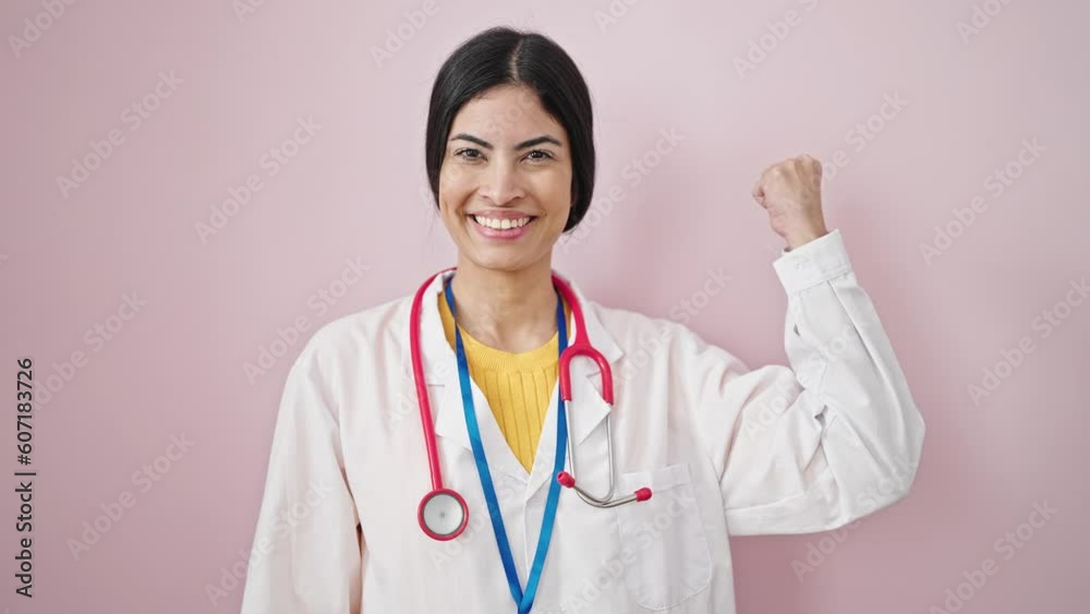 Young beautiful hispanic woman doctor smiling confident doing strong gesture over isolated pink background Young beautiful hispanic woman doctor smiling confident doing strong gesture over isolated pink background