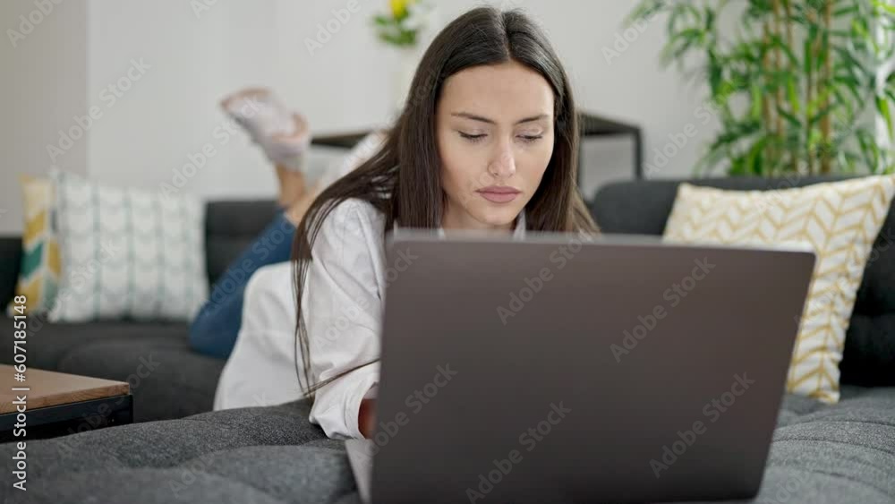 Young beautiful hispanic woman using laptop lying on sofa at home Young beautiful hispanic woman using laptop lying on sofa at home