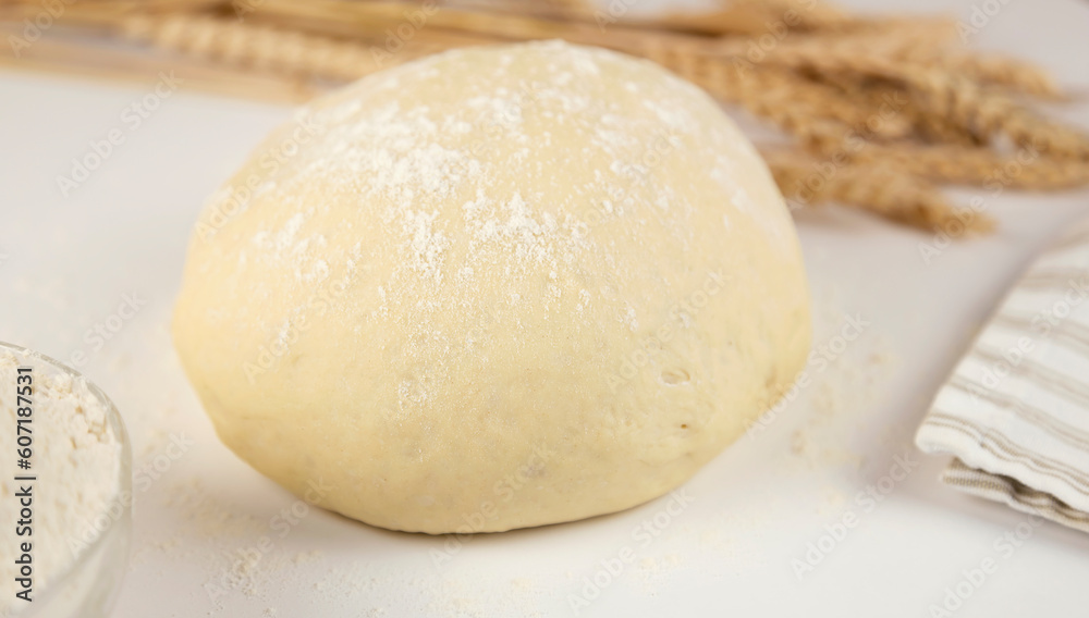Raw dough, flour and ears of wheat on white background, close-up front view. Home baking concept. Raw dough, flour and ears of wheat on white background, close-up front view. Home baking concept.