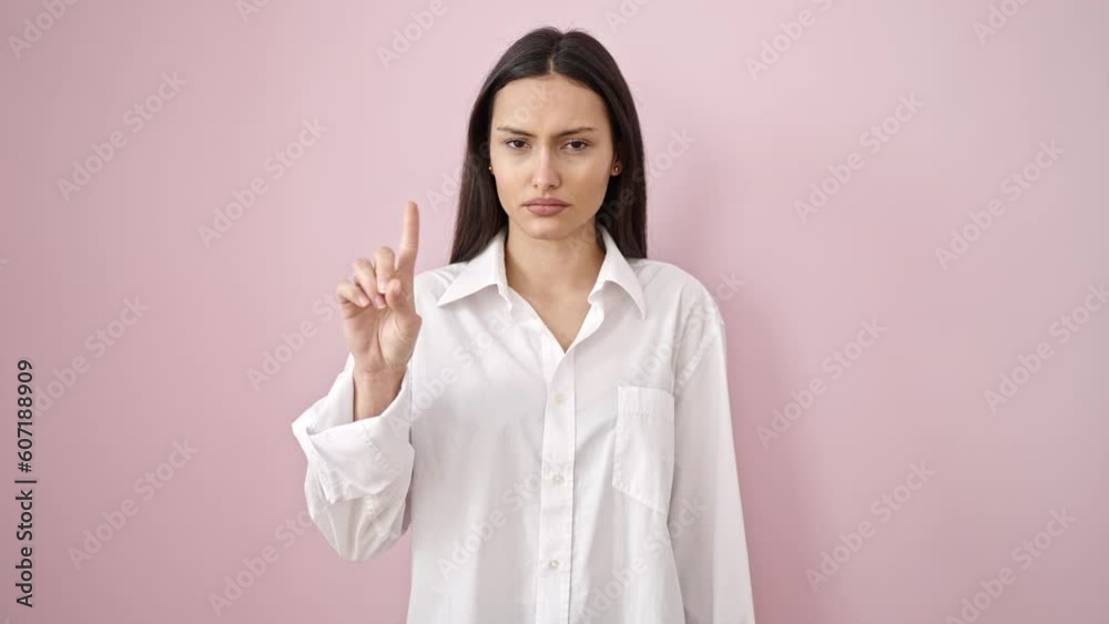 Young beautiful hispanic woman saying no with finger over isolated pink background Young beautiful hispanic woman saying no with finger over isolated pink background