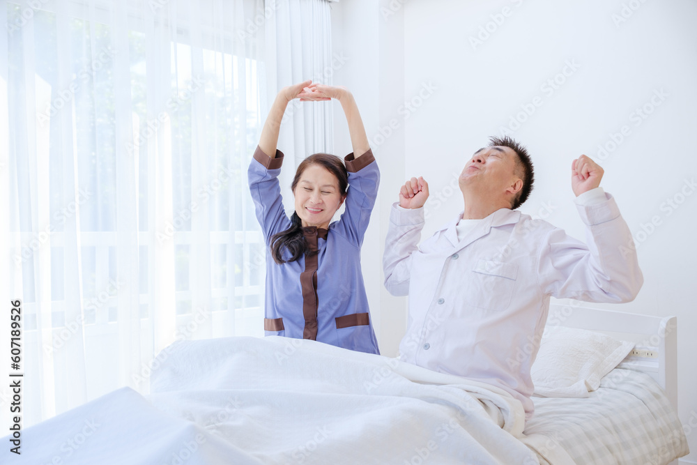 Obraz premium ベッドでストレッチをするシニア夫婦