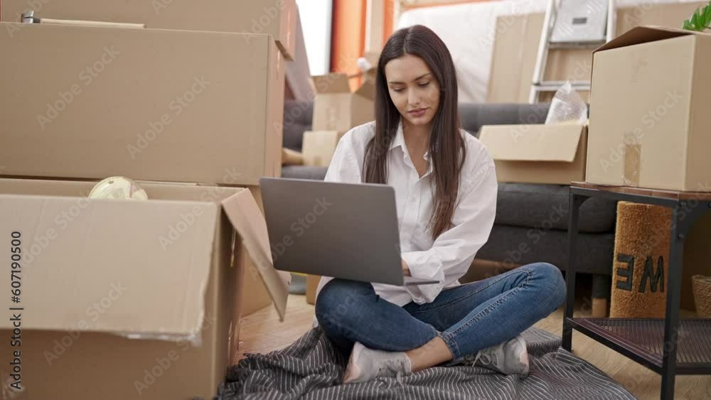 Young beautiful hispanic woman using laptop sitting on floor at new home Young beautiful hispanic woman using laptop sitting on floor at new home