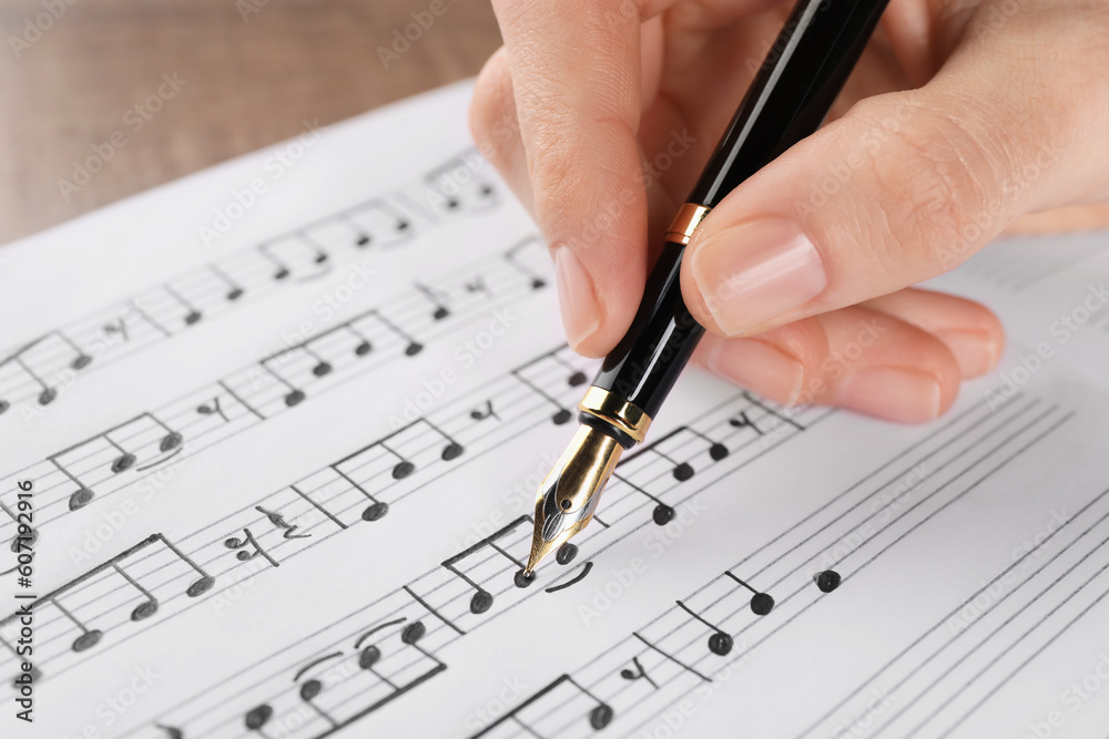 Woman writing musical notes with fountain pen on sheet of paper, closeup Woman writing musical notes with fountain pen on sheet of paper, closeup