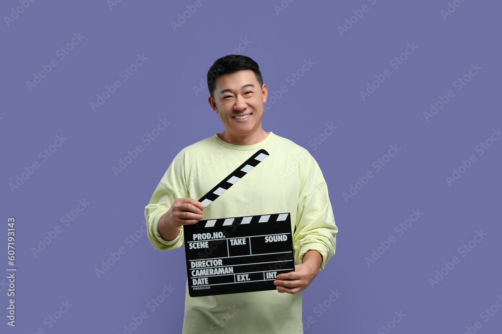 Happy asian actor with clapperboard on purple background. Film industry Happy asian actor with clapperboard on purple background. Film industry