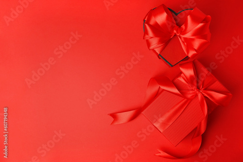 Beautiful gift boxes with bows on red background, flat lay. Space for text