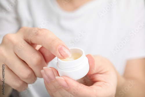 Woman taking cosmetic petrolatum from jar, closeup