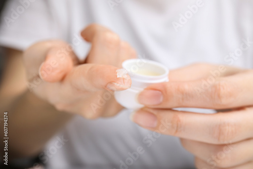 Woman taking cosmetic petrolatum from jar, closeup