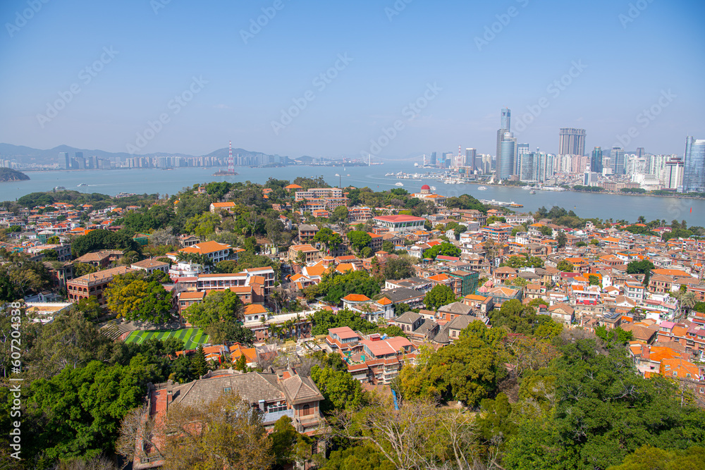 GULANGYU, XIAMEN, CHINA. February 21st, 2021: Aerial view of Gulangyu island with Xiamen skyline. Blue sky with copy space for text, panorama
