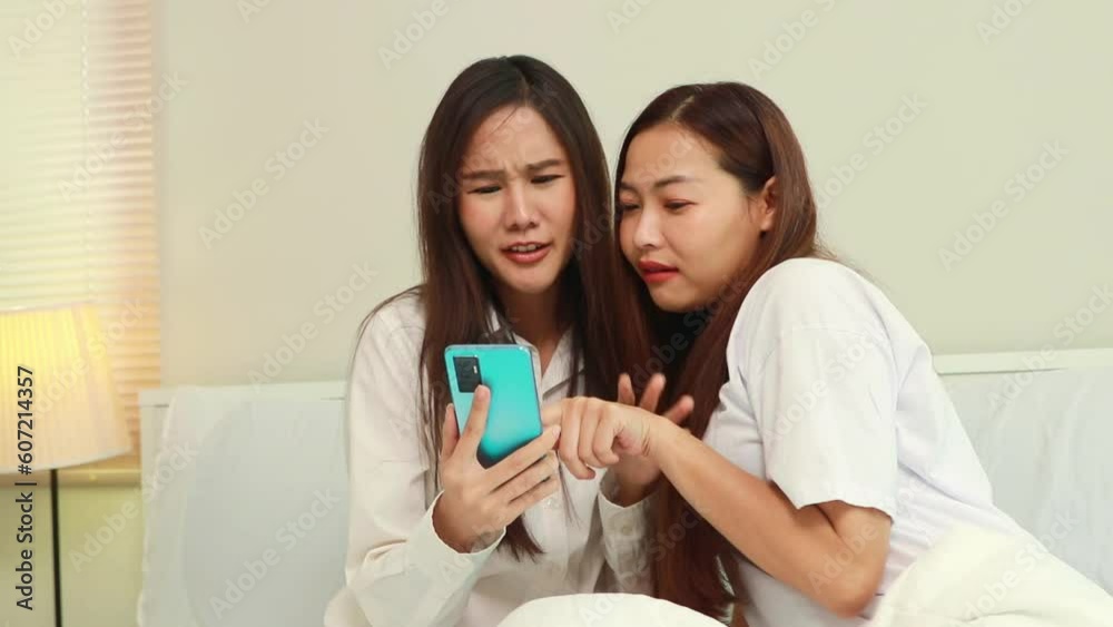 Two intimate women gossip before going to bed in their bedroom at home and whispering secrets. Gossip about people on smartphones with satisfaction, long fun and happiness. Two intimate women gossip before going to bed in their bedroom at home and whispering secrets. Gossip about people on smartphones with satisfaction, long fun and happiness.