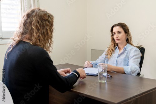 Professional female psychologist listening to her patient during therapy session at her office.