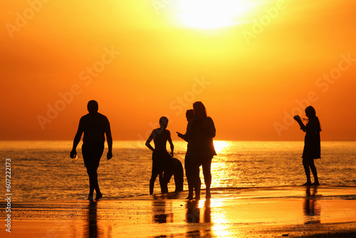Silueta de familia em por do sol intenso e quente aproveitando as ferias de verao na praia. photo