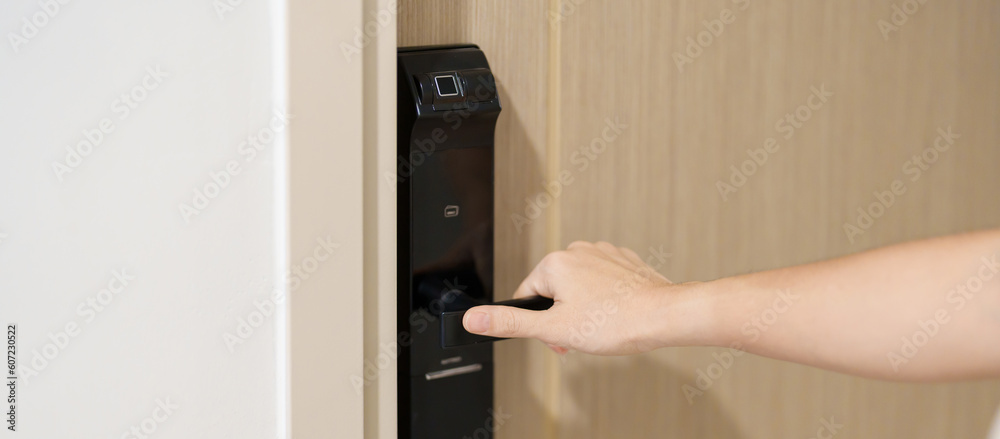 Hand using smart digital door lock while open or close the door at home or apartment. NFC Technology, Fingerprint scan, keycard, PIN number, smartphone, electrical and contactless lifestyle concepts Hand using smart digital door lock while open or close the door at home or apartment. NFC Technology, Fingerprint scan, keycard, PIN number, smartphone, electrical and contactless lifestyle concepts