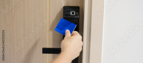 Hand using keycard for smart digital door lock while open or close the door at home or apartment. NFC Technology, Fingerprint scan, PIN number, smartphone and contactless lifestyle concepts