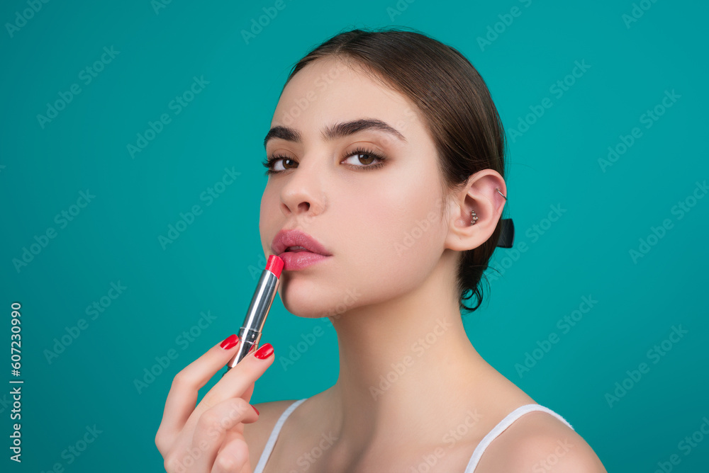 Obraz premium Lipstick, beauty and cosmetics. Beautiful woman applying lipstick on lips. Mockup for cosmetics, makeup. Lips color product, balm cosmetic on studio background.
