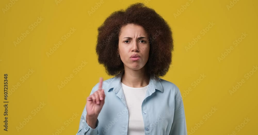 Young african american woman saying no with in dex finger gesture standing over orange studio background Young african american woman saying no with in dex finger gesture standing over orange studio background