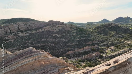 Aerial shot of the mountainous and rocky terrain of Vazquez Rocks combined with a lush green landscape creating unique peeks and valleys as the sun begins to set on this otherworldly landscape. photo