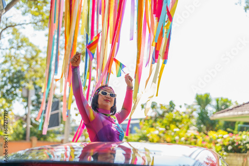Happy Asian woman support LGBT pride parade in car. with Rainbow of LGBTQ or LGBTQIA.